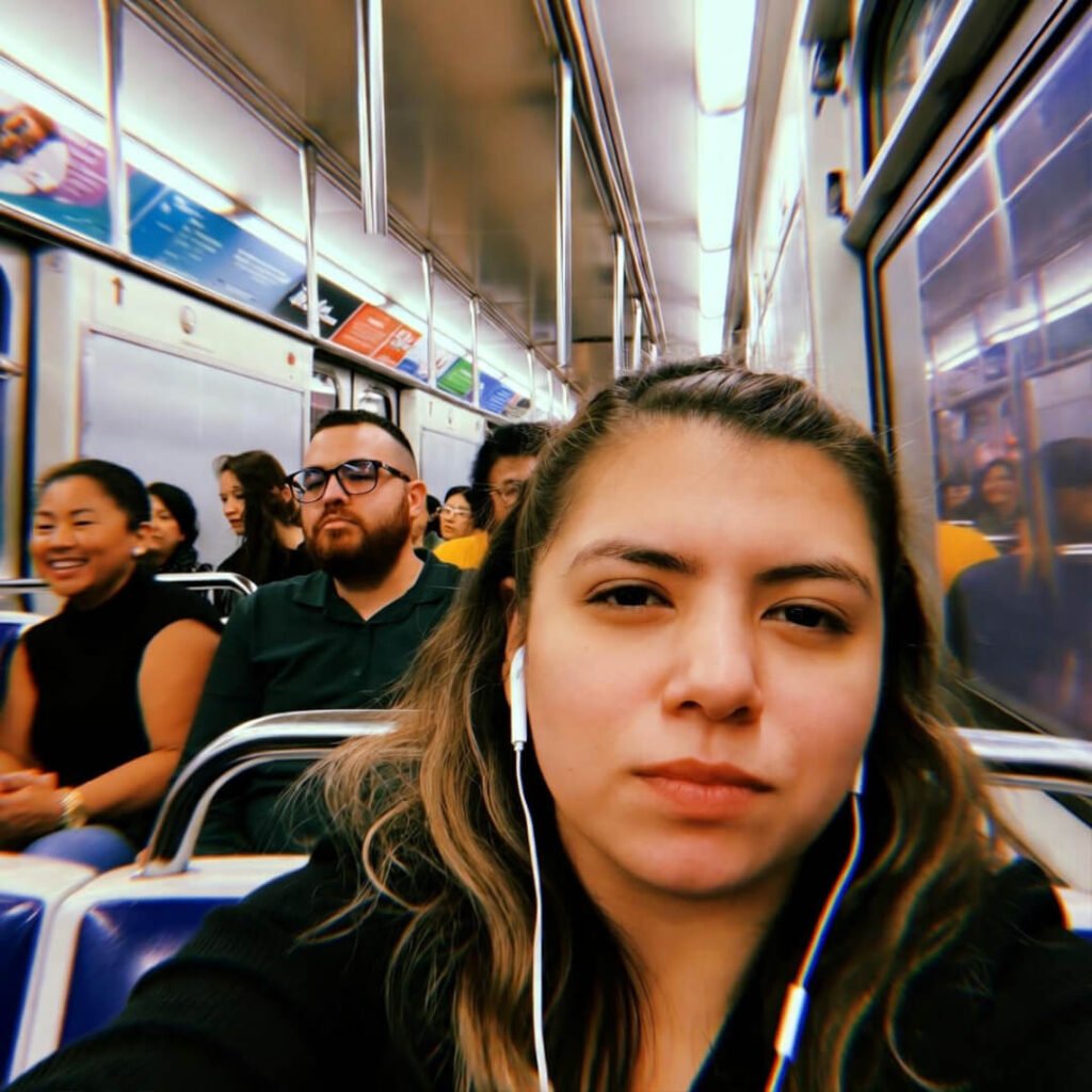Eye-roll selfie on crowded L train with AirPods.