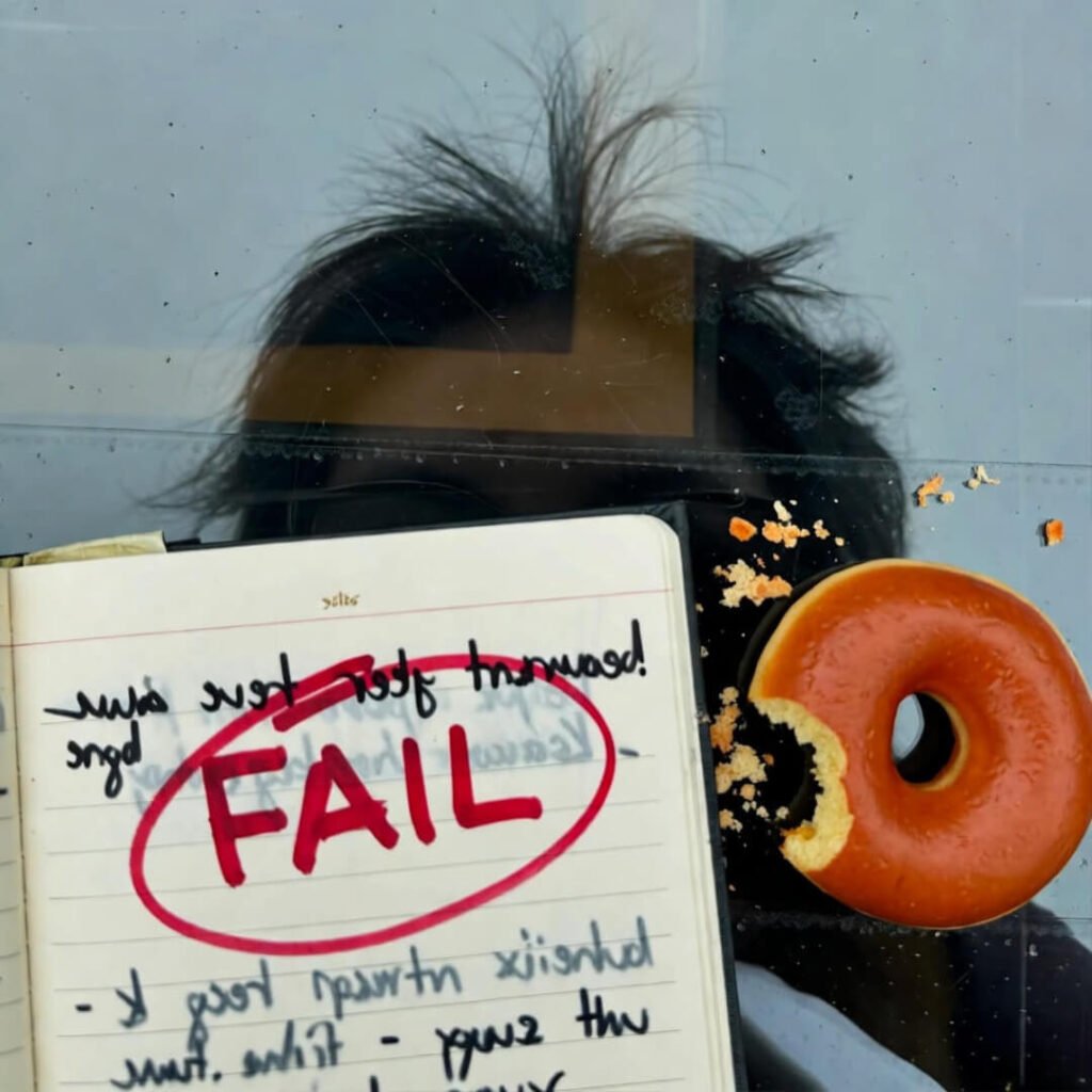 Journal with red FAIL, donut crumbs, gray Seattle reflection.