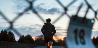 Powerful Motivational Sports Quotes to Inspire You During Tough Times Lone runner at dawn on rainy track.